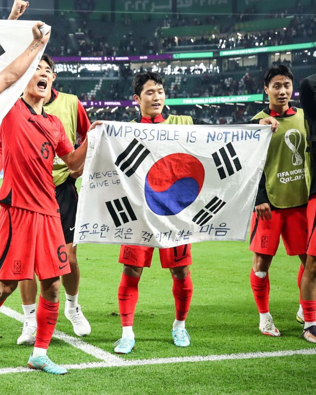 Jogadores com a bandeira da Coreia com a frase de Deft